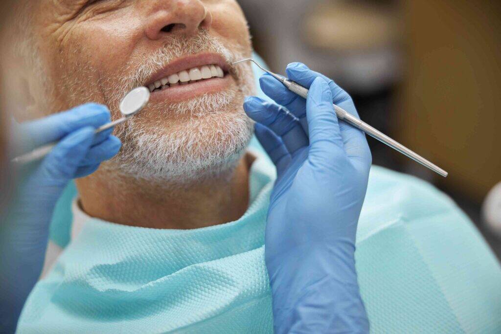 Senior patient receiving a dental exam with mirror and explorer.